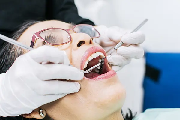 paciente siendo tratada por un dentitas mientras abre la boca
